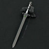 A detailed metal sword keychain featuring a blade, hilt, and a green ornament, resting on a dark rock.