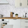 A kitchen cabinet and backsplash featuring white marble-patterned wallpaper and light wood countertops.