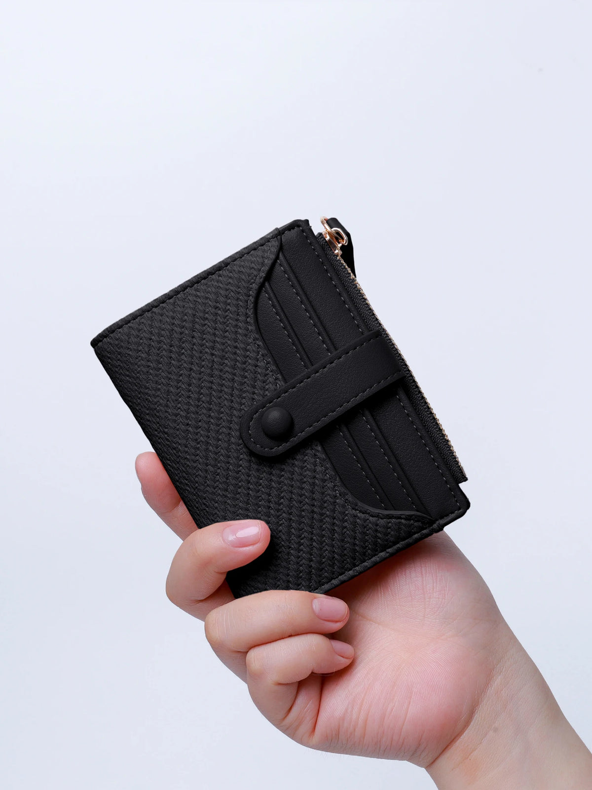 A hand holds a black premium PU leather bi-fold wallet with a zipper closure.