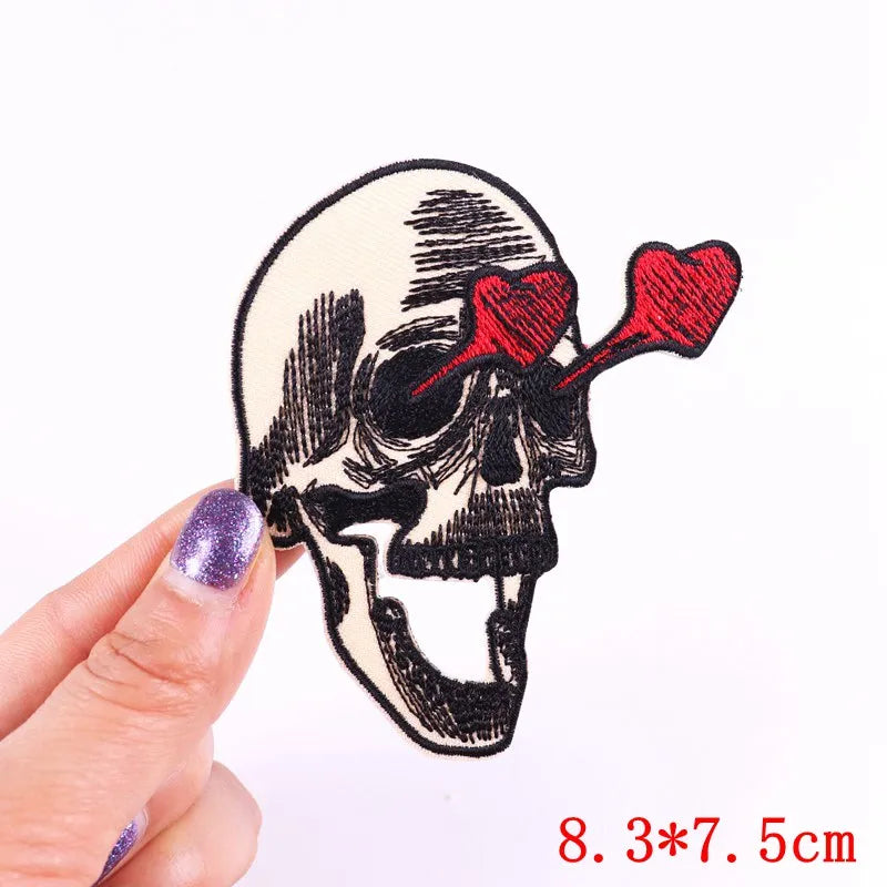 An embroidered rose skull patch with iron-on backing is held by a hand.