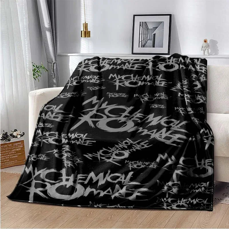 Black fleece throw blanket featuring My Chemical Romance band graphics draped on a white sofa.