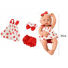 A baby doll with a red bow wearing a white outfit and a red accessory set.