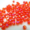 Haufen kleiner, facettierter, durchscheinender orange-roter Kristallperlen zum Schmuckherstellen.