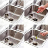 A hand is using a flexible drain snake to clear a clog in a kitchen sink.