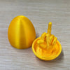 A bright yellow Easter egg shaped like a hand giving the middle finger, used as desk decor.