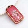A red TPU protective key case with gold accents is shown resting on a white surface.