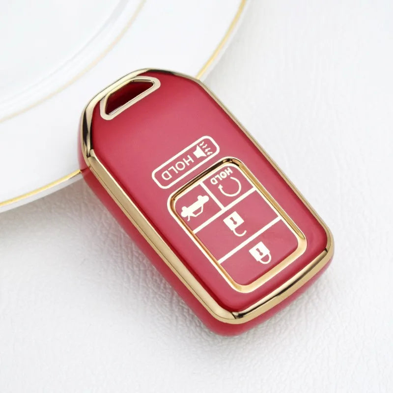 A red TPU protective key case with gold accents is shown resting on a white surface.