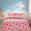 Pink strawberry print duvet cover set with matching pillowcases on a white bed against a light blue wall.