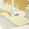 A white silicone mat with textured ridges is placed under a faucet, designed to catch water splashes.