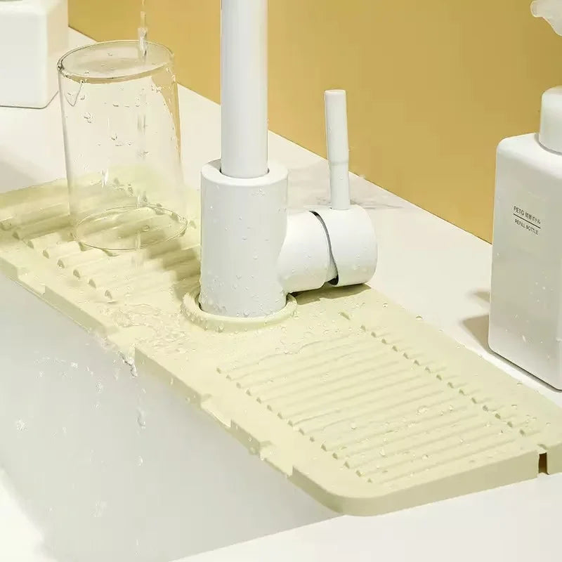 A white silicone mat with textured ridges is placed under a faucet, designed to catch water splashes.