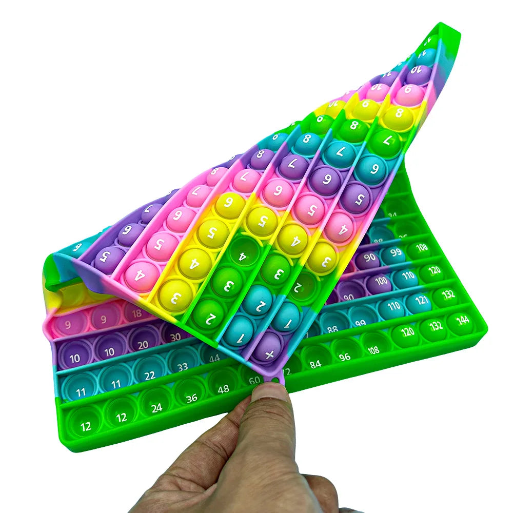 A hand holds a push bubble math game toy showing colorful numbered bubbles for addition and multiplication learning.