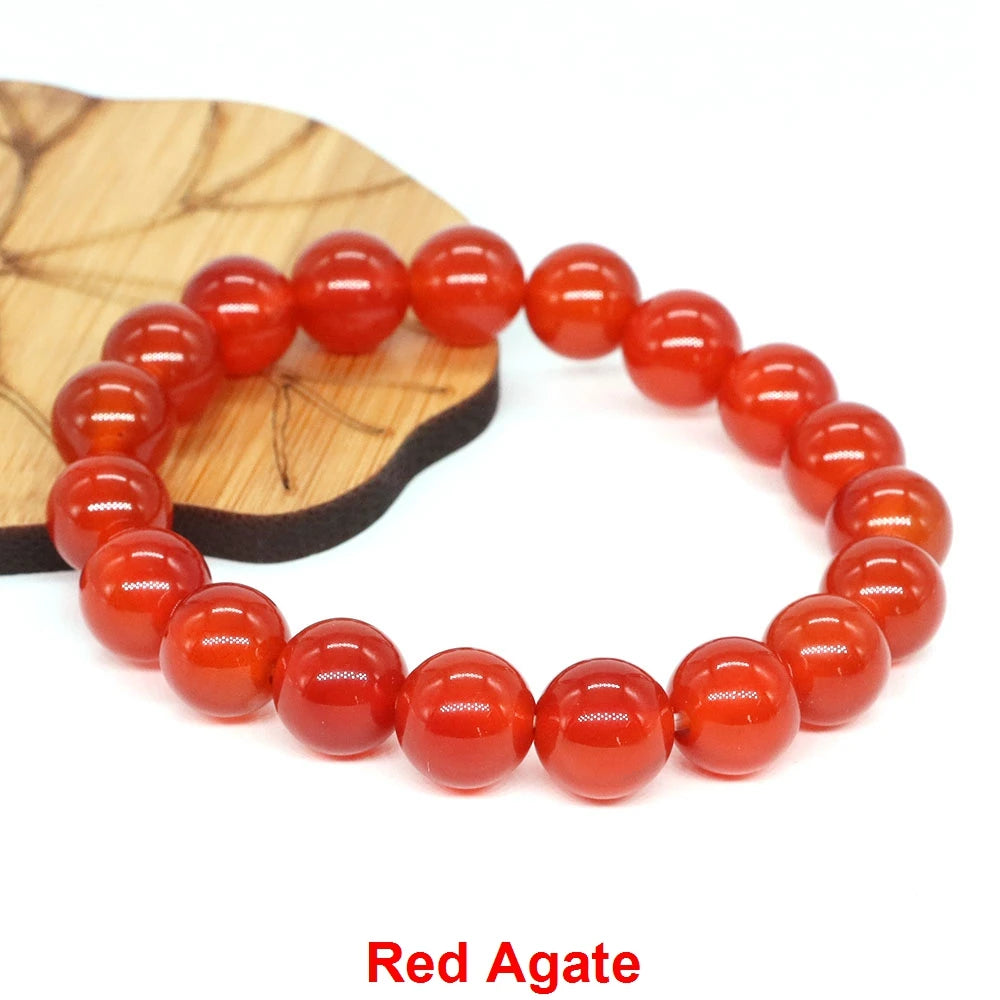 A bracelet made of smooth, round red agate beads resting on a wooden surface.