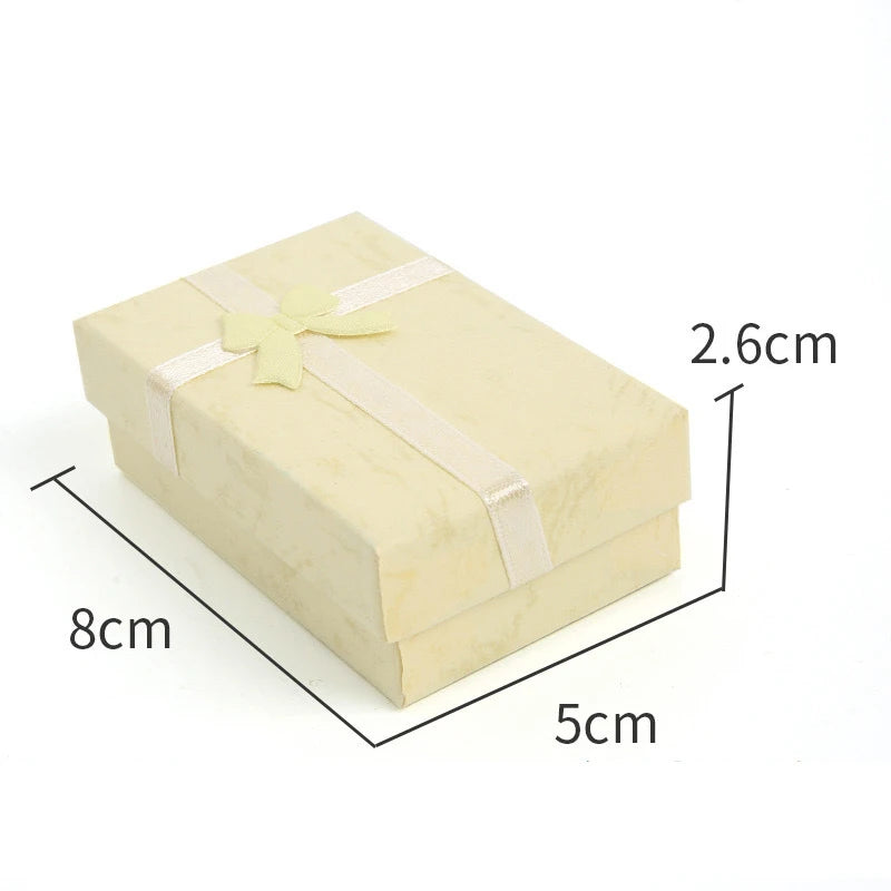 A rectangular light yellow velvet jewelry gift box with a pale yellow ribbon tied on top.
