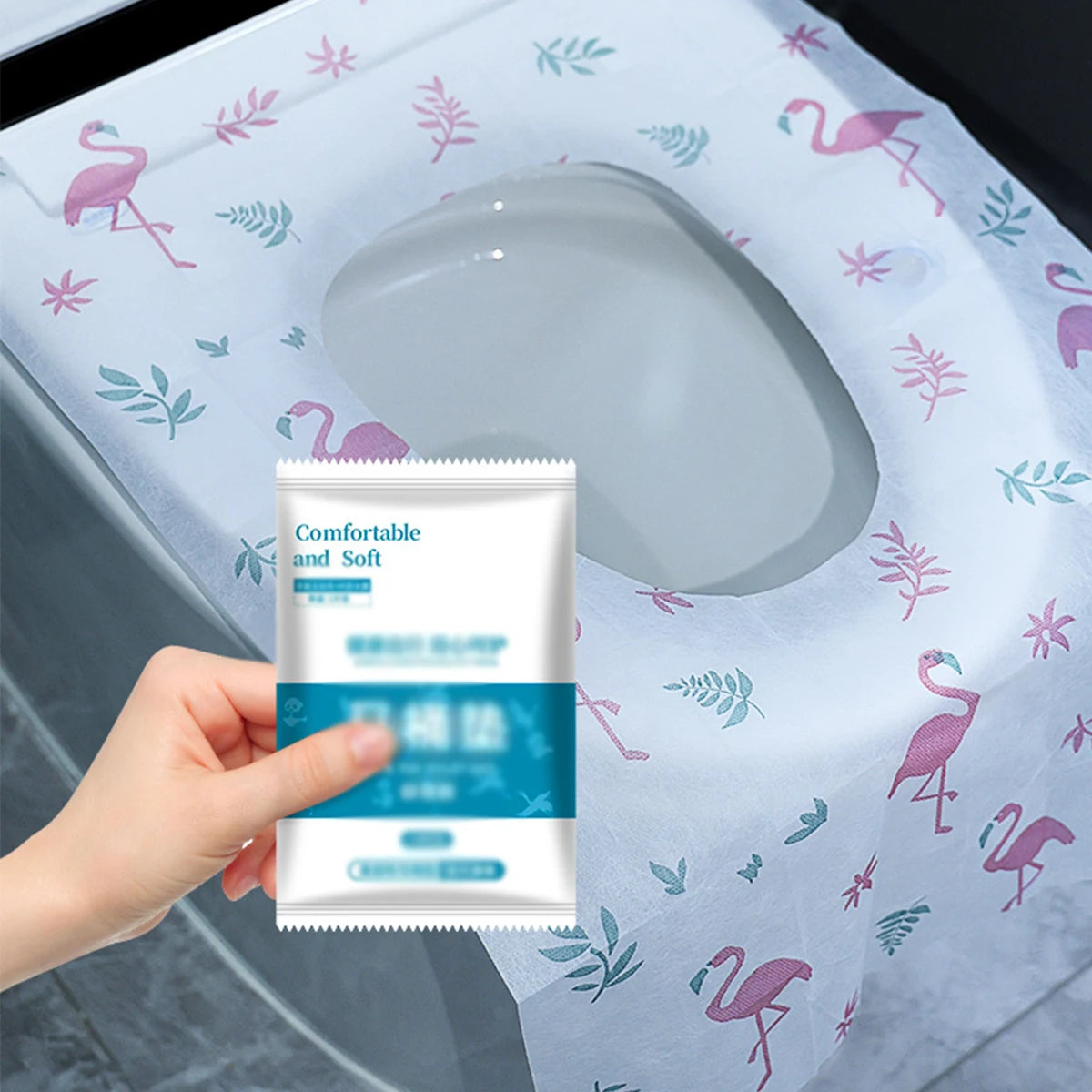 A hand holds a package of disposable toilet seat covers for travel and public restrooms against a light blue patterned surfac