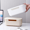 A hand is lifting a white plastic cable management box with vertical ridges, demonstrating the dustproof power strip organize