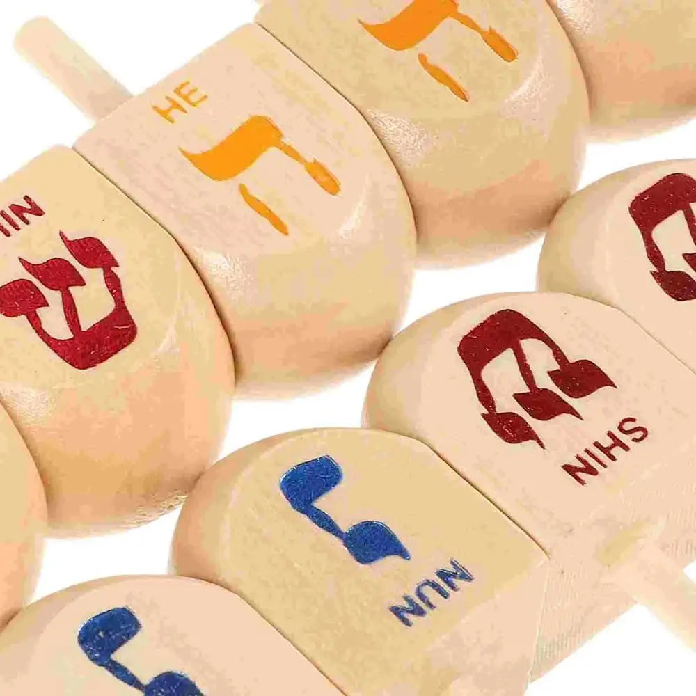 A close-up of several wooden spinning tops with engraved letters and symbols for Hanukkah and kids' play.