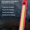 A red and black multifunctional LED handheld work light with a bright yellow floodlight, shown outdoors.