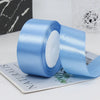 A roll of light blue satin ribbon used for gift wrapping or DIY crafts, shown next to a piece of paper.