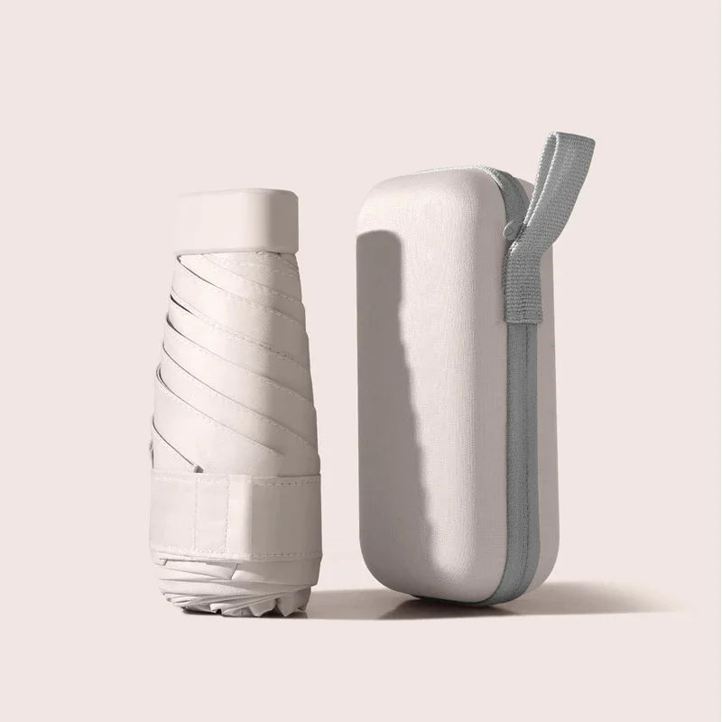 A white compact travel umbrella is shown with its protective capsule case attached.