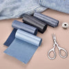 Rolls of denim iron-on patches and a pair of scissors on a light pink background