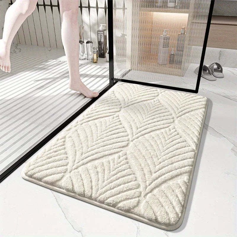 A beige plush velvet bathroom mat with a textured pattern is shown on a white marble floor.