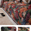 A richly colored floral jacquard sofa blanket with tassels draped over a sofa.