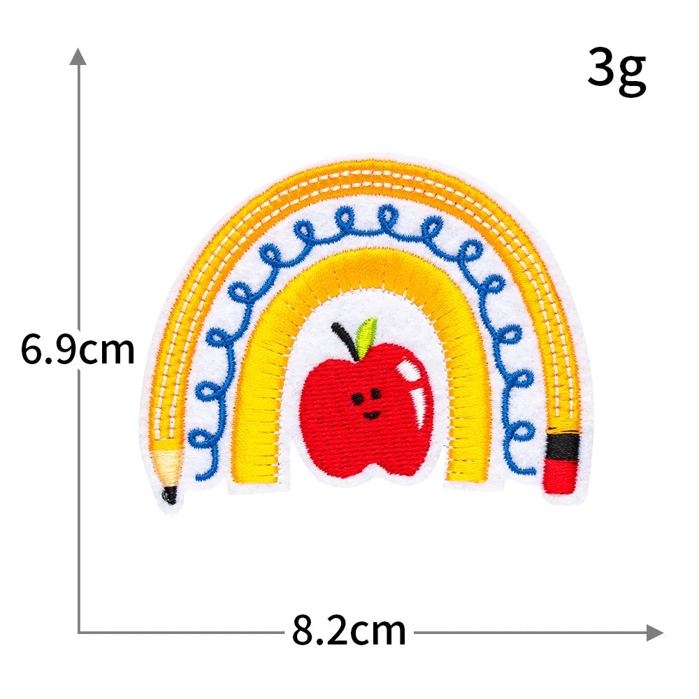 A yellow, blue, and white rainbow shape with a red apple in the center, measuring 6.9cm high and 8.2cm wide.