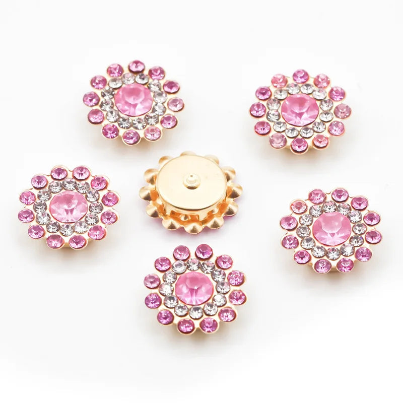 A collection of pink and clear rhinestone flowers, some gold-toned, arranged on a white background.