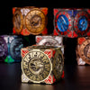 A close-up of a premium metal spinner dice cube with a detailed dragon design and numbered faces, set against a dark backgrou