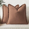 A tan boho fringe throw pillow cover with a natural linen texture resting on a light-colored sofa.