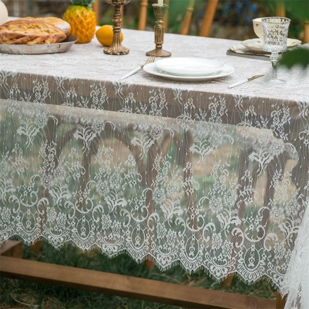Elegant white lace tablecloth with French retro floral design set on a rustic wooden table.