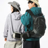 A person wearing a teal jacket and a beige hat is carrying a black tactical backpack.