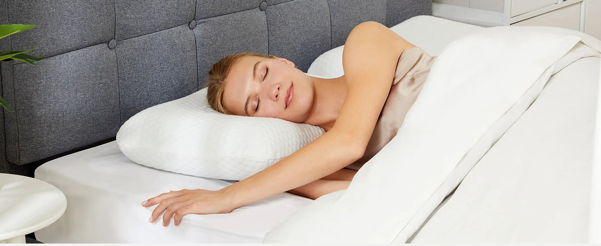 A woman is sleeping comfortably on a white memory foam pillow in a modern bedroom setting.