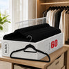 A stack of black velvet non-slip hangers with rotating hooks displayed in a white box on a wooden shelf.