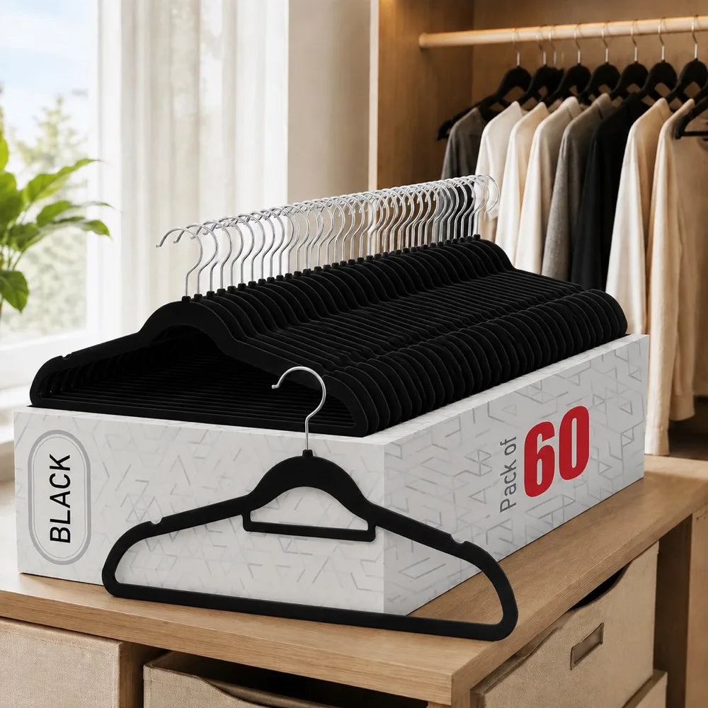 A stack of black velvet non-slip hangers with rotating hooks displayed in a white box on a wooden shelf.
