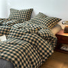 A plaid duvet cover in olive green and beige tones with a grid pattern displayed on a bed.