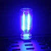A glass accent USB touch dimmable LED night light glowing bright blue on a dark surface.