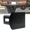 Black 2-inch trailer hitch receiver plug cover installed on a vehicle's rear bumper.