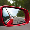 A close-up view of a red car mirror showing a heart decal that reads I love you drive safe