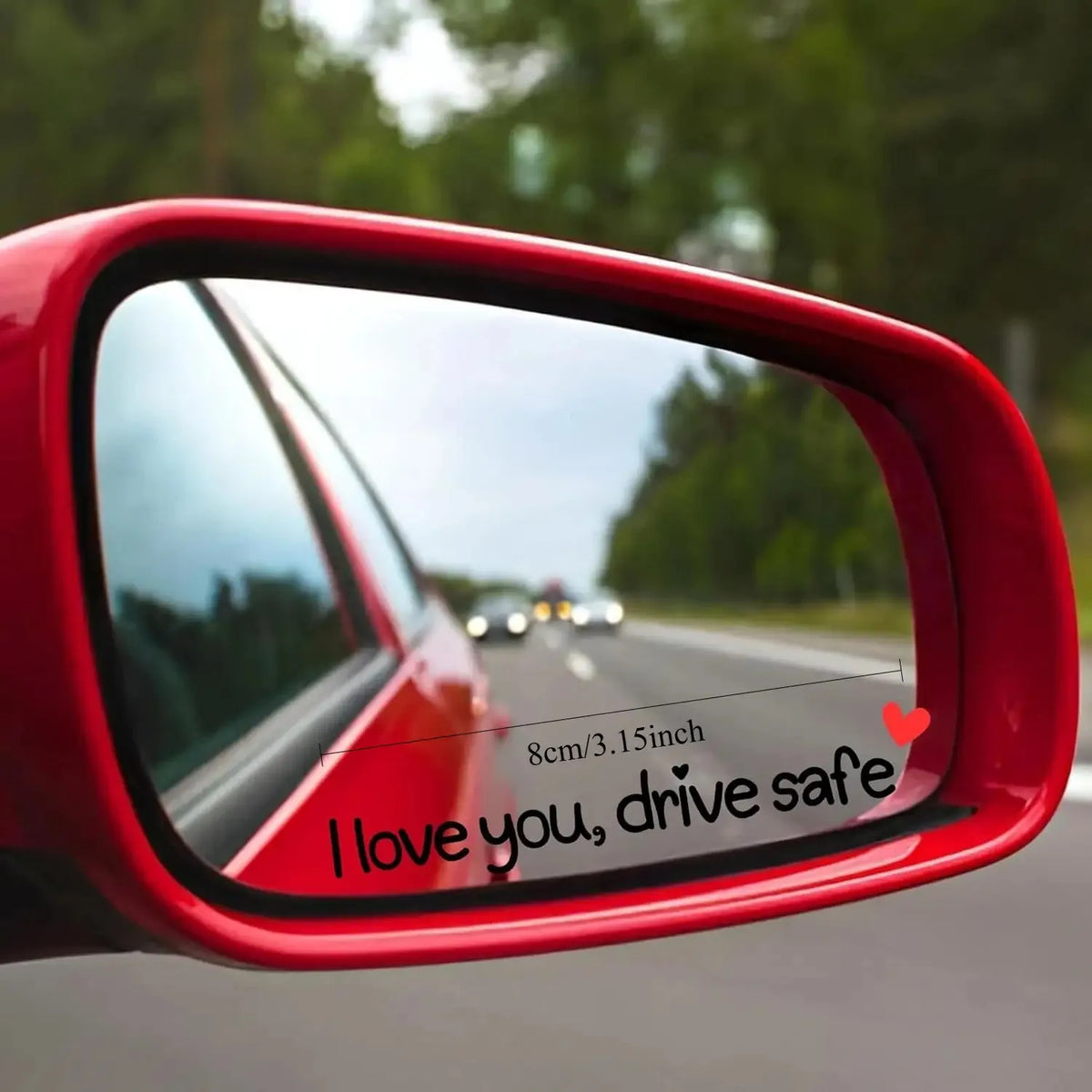 A close-up view of a red car mirror showing a heart decal that reads I love you drive safe