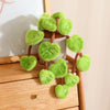 A potted plant made of soft green faux leaves resembling a pothos, displayed on a wooden surface.