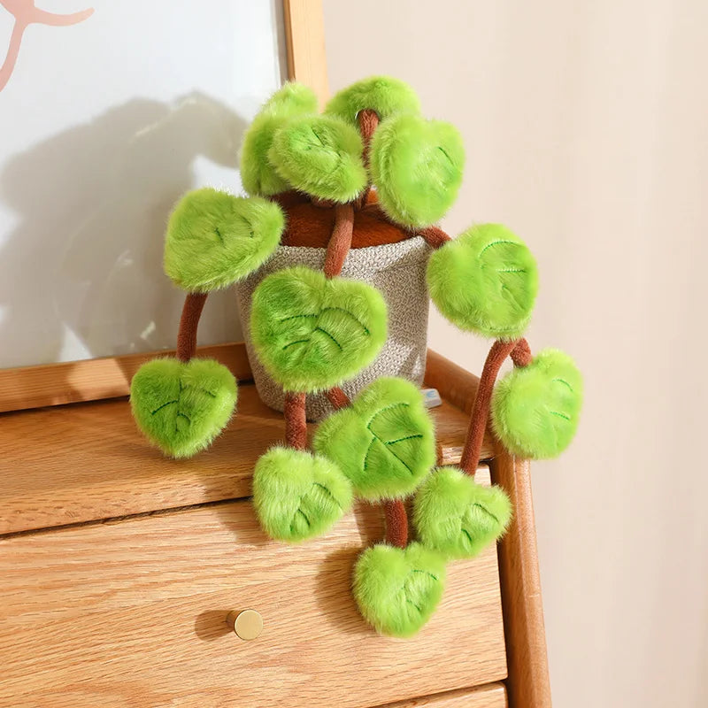 A potted plant made of soft green faux leaves resembling a pothos, displayed on a wooden surface.