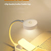 A small, flexible LED book light illuminates a page of an open book.