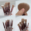 A collection of thirteen makeup brushes in various shades and sizes displayed against a white background.