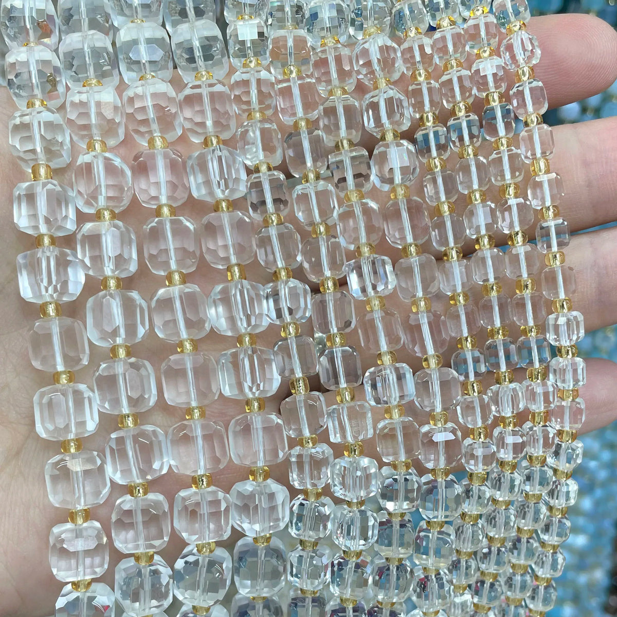 A close-up of clear natural stone square faceted beads strung together on a string for jewelry making.