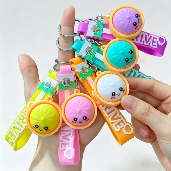 Eine Hand hält mehrere bunte Fidget-Dumpling-Anhänger mit verschiedenen Pastellfarben und Charms.