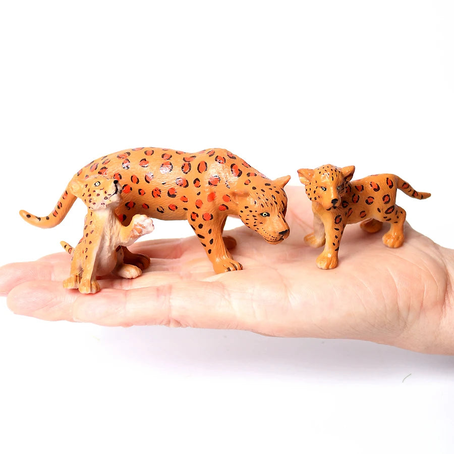 A pair of realistic orange and brown animal figurines, resembling foxes or canids, are held in a person's hand.