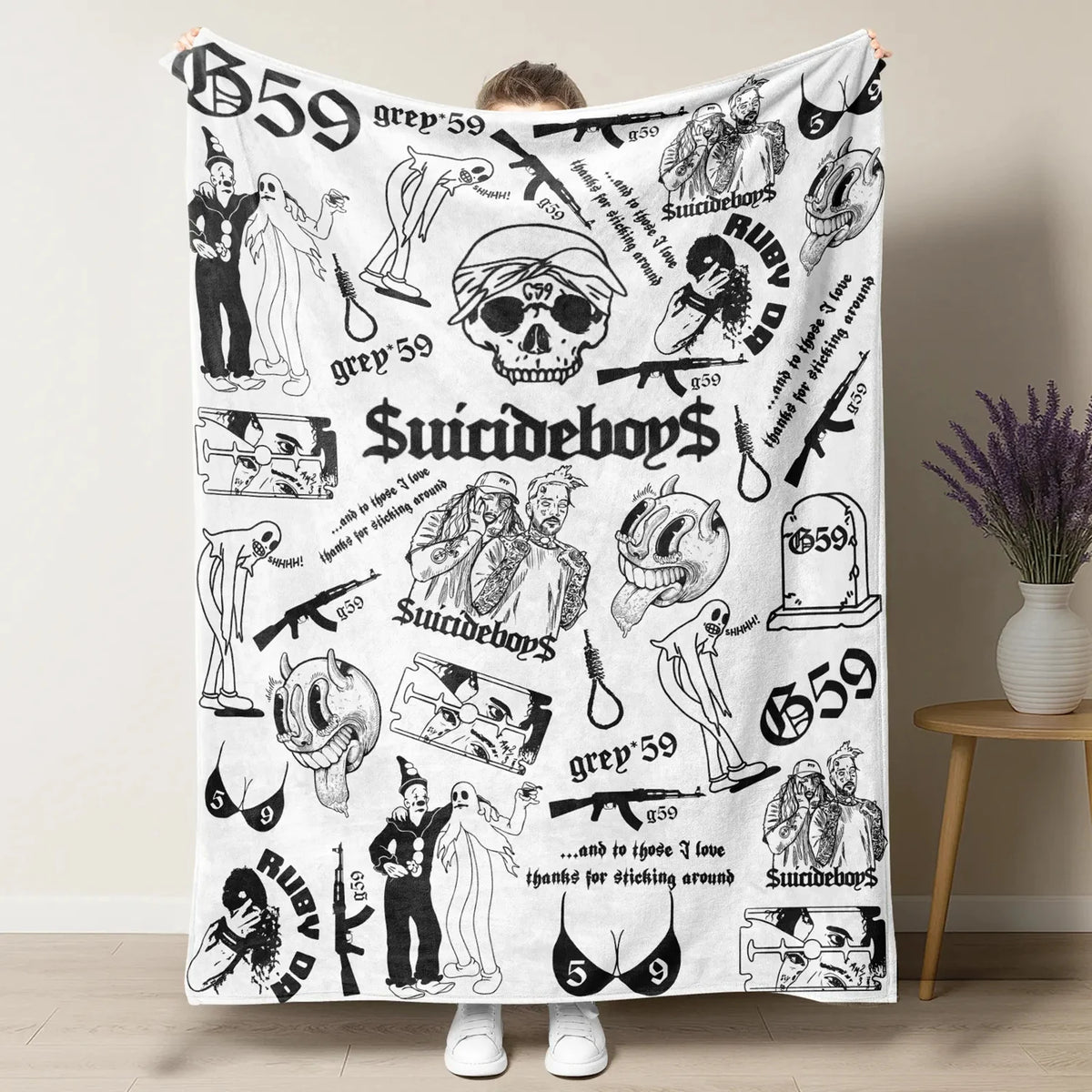 A white throw blanket featuring various black and white illustrations of skulls, clowns, and horror themes.
