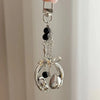 Silver metal music note charm hanging from a keyring.