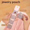 A hand holds a portable jewelry pouch with four compartments for organizing rings, bracelets, earrings, and necklaces.